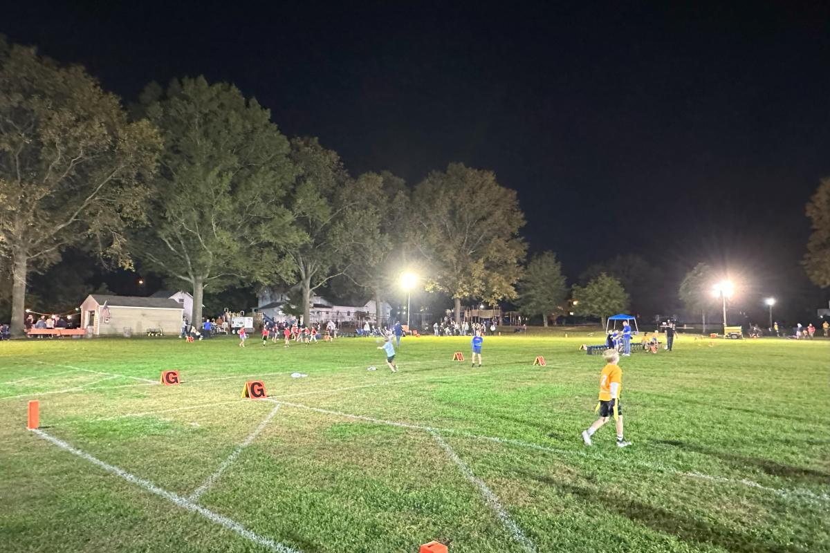 children playing flag football under the lights