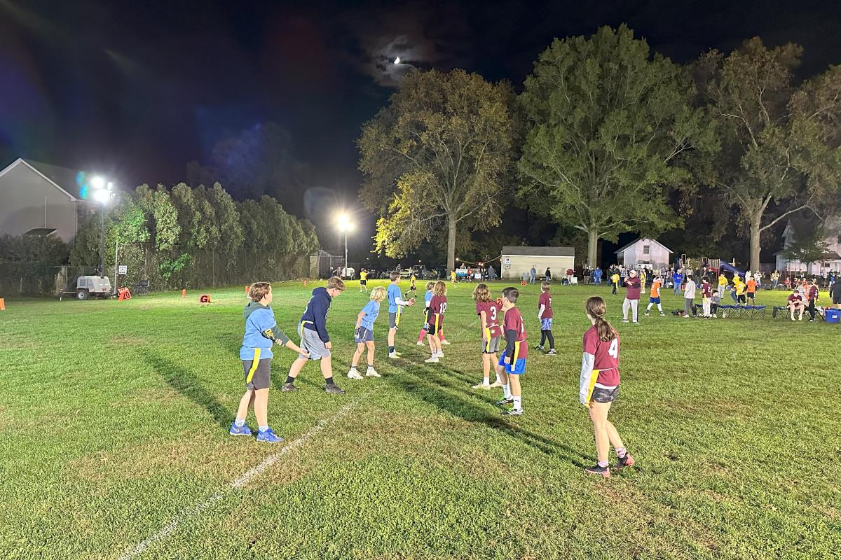 Children playing flag football in the park at night