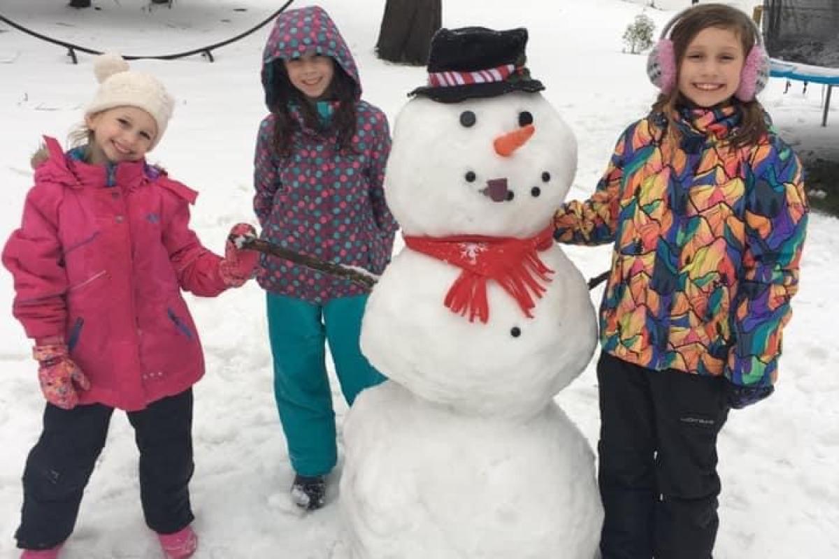 Three children with snowman sculpture