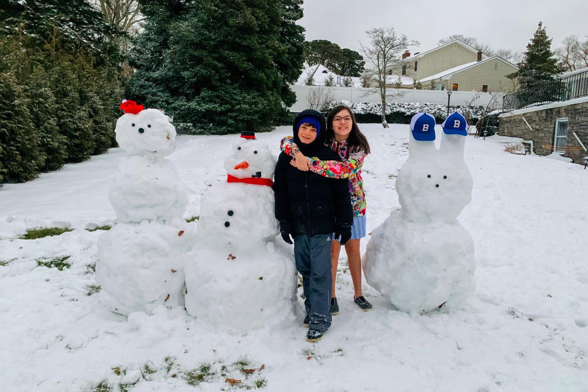 Two children with several snowman sculptures
