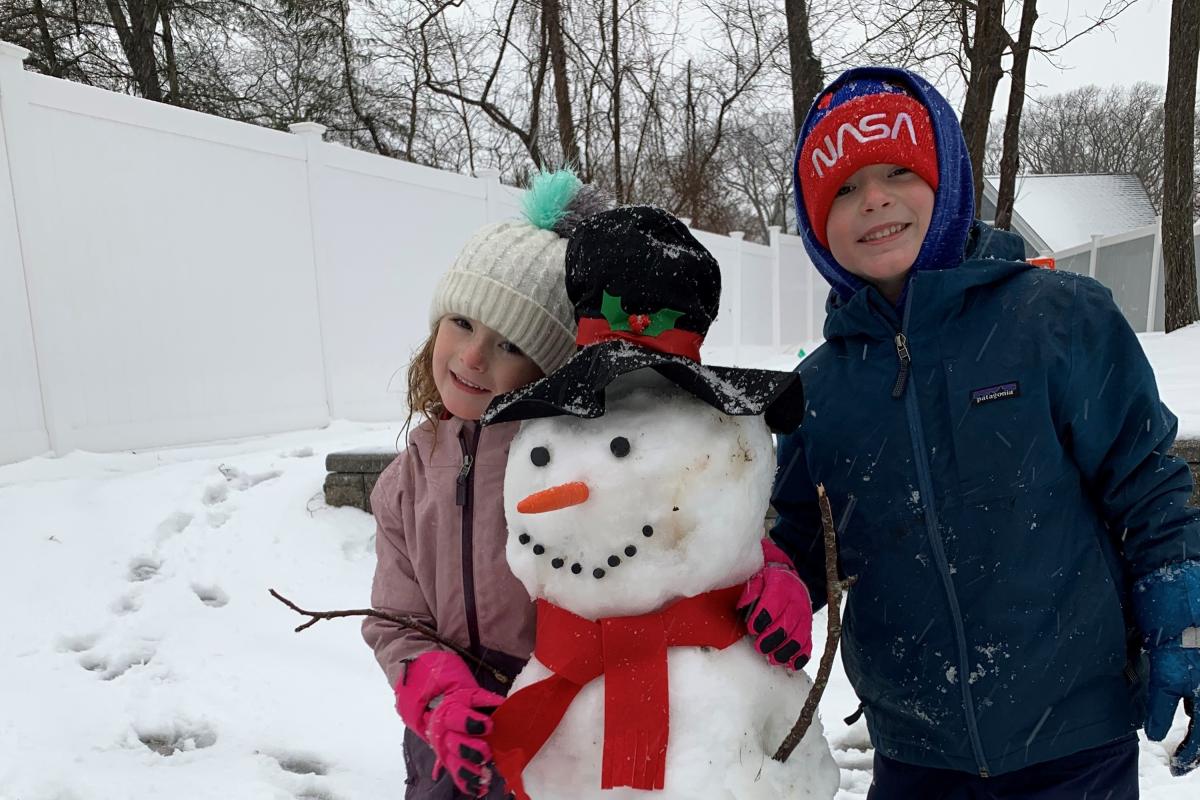 Two children with a snowman sculpture